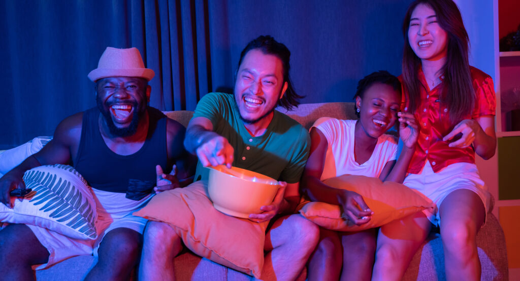 Group of friends having fun at home watching movies and enjoying and celebrating together